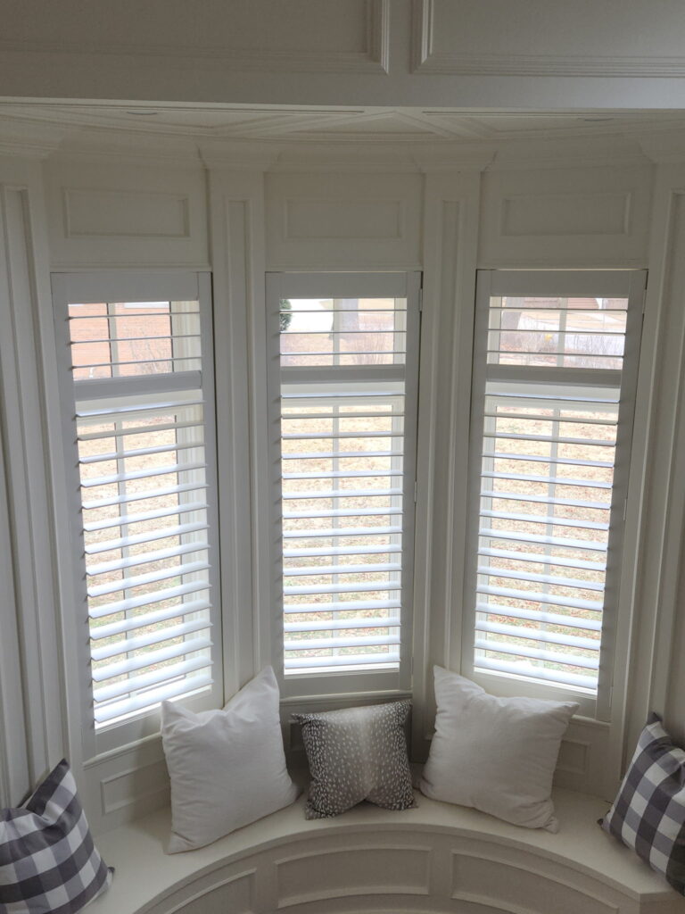 hunter Douglas shutters sitting in a bay window with a cozy reading nook