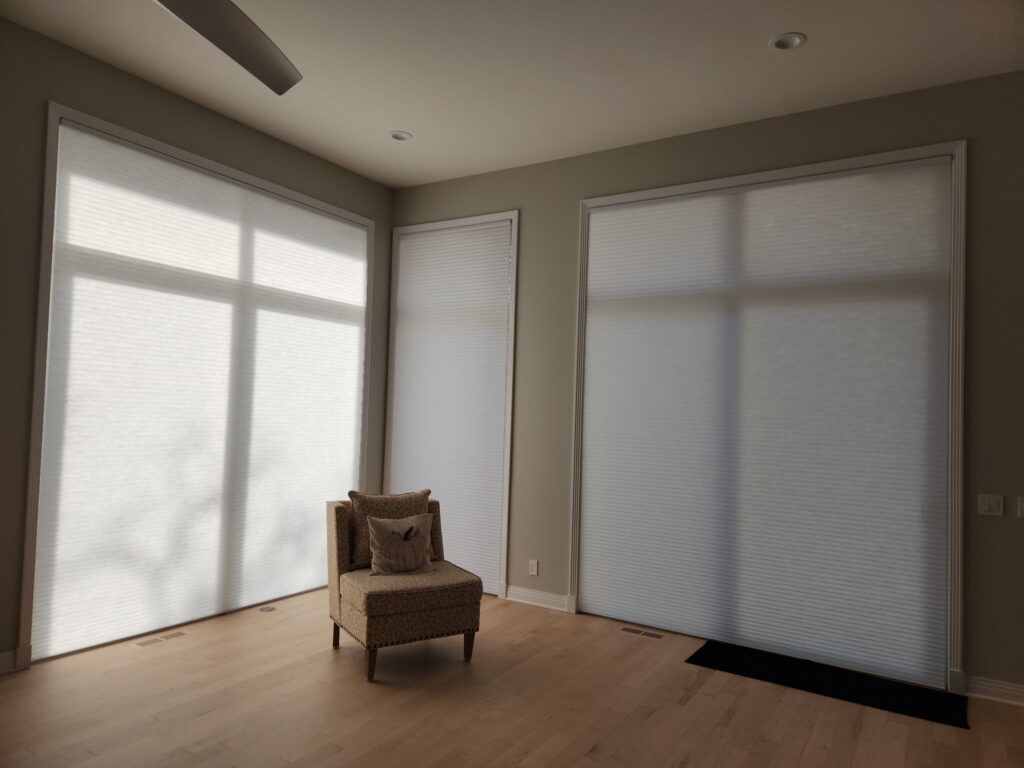 Multiple Hunter Douglas motorized Applause Honeycomb shades hanging in a cozy living room.