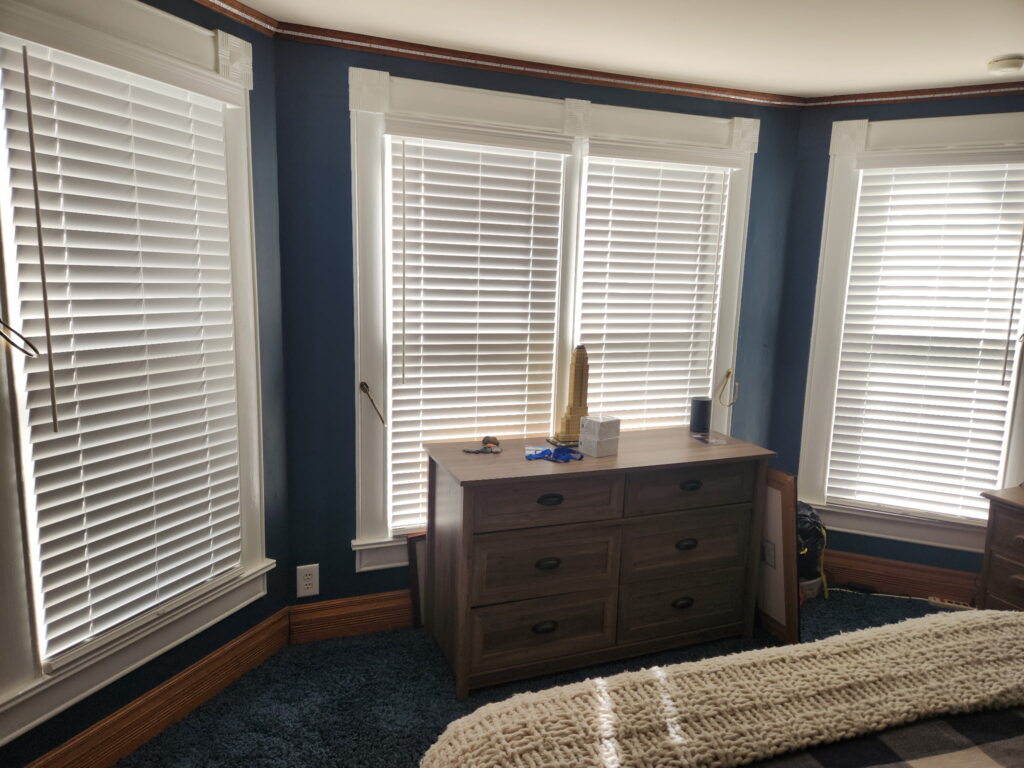 Hunter Douglas EverWood Faux Wood Blinds hanging in a bedroom with multiple windows