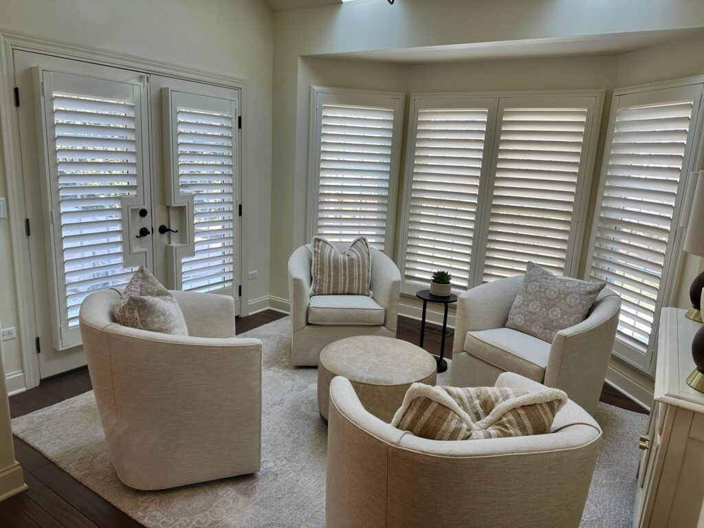 A full living room of Hunter Douglas plantation shutters over the windows and door. Installed by Ogden blinds in Warrenville, IL