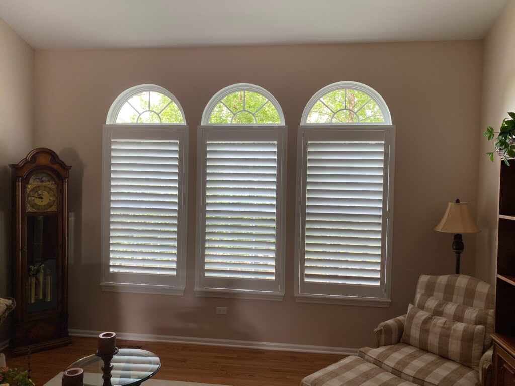 Three Hunter Douglas shutters with smaller, rounded, decorative windows above.