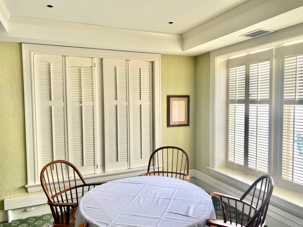 Multiple Hunter Douglas shutters in a dining room.