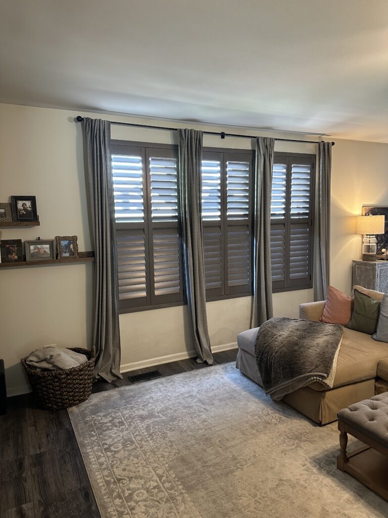 Dark wood Hunter Douglas shutters against a while wall. Installed by Ogden Blinds