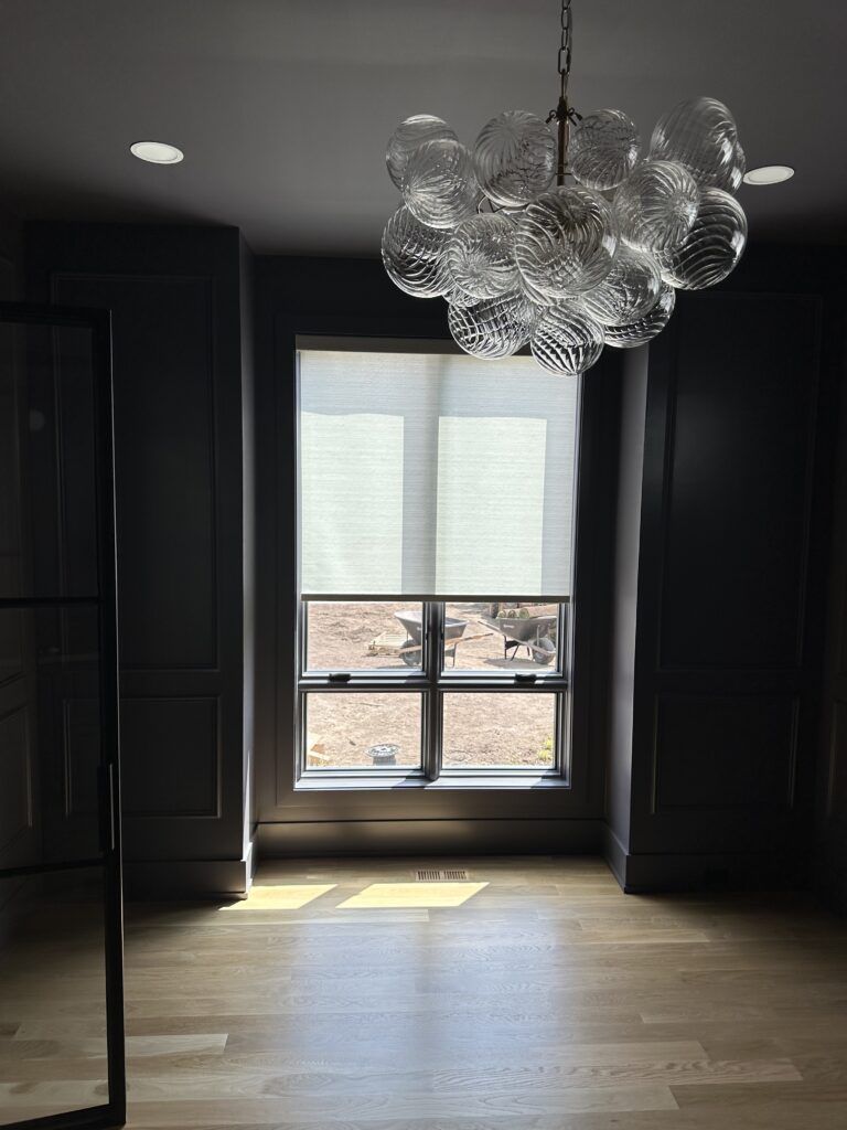 White Hunter Douglas Roller shade in a black room with funky lighting.