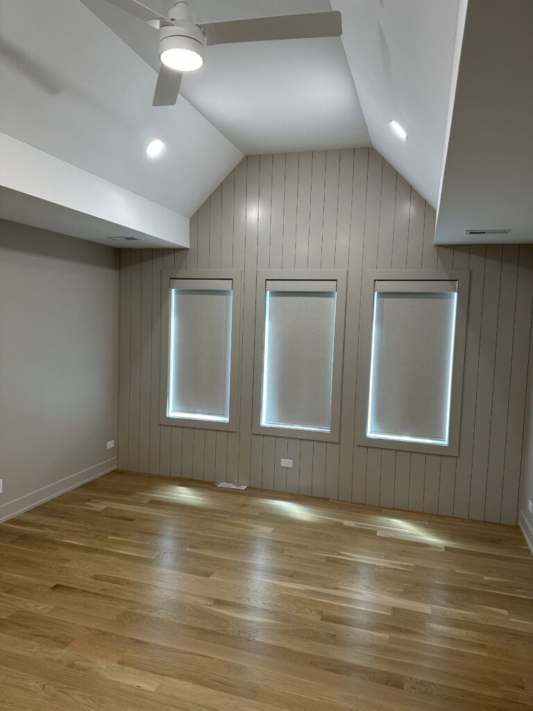 Three gray Hunter Douglas roller shades hanging from three windows next to each other, creating a monochrome look with matching gray walls