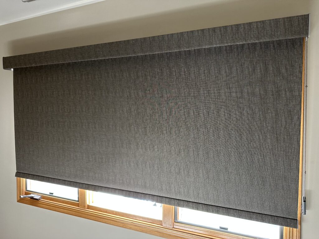 Hunter Douglas Designer Roller Shade with dark gray, textured fabric on heather gray walls, complete with vibrant wood trim